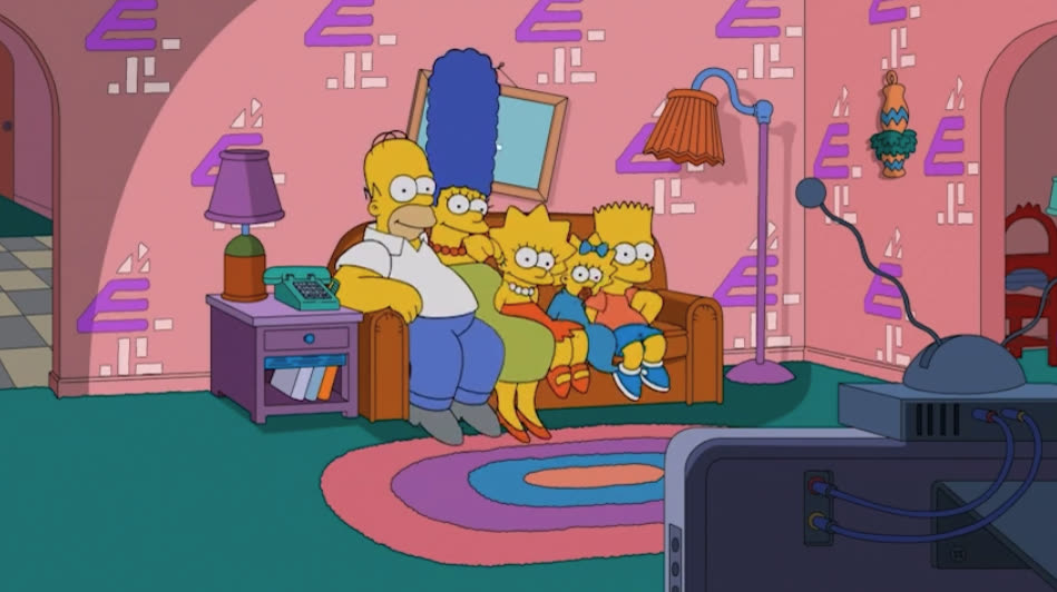 The Simpsons on their couch, the living room wallpaper covered in E4 logos